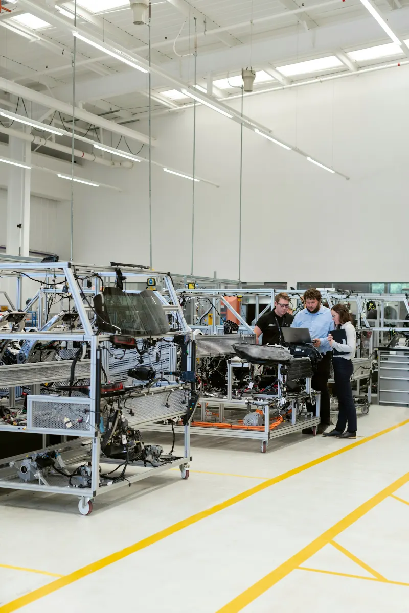 Engineers reviewing data on a laptop beside an assembly line